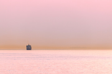 Container ship and line of haze in pink afterglow