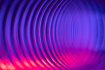 Closeup of coiled metal spring with sufficiently high strength and elastic properties in neon blue...