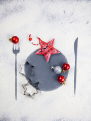Christmas minimal table setting decoration with cookies, stars and balls. White background with flour imprint of fork, plate and knife. Christmas pattern decoration. Christmas aesthetics