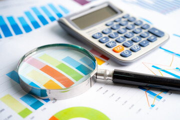 Magnifying glass and calculator on charts graphs paper. Financial development, Banking Account, Statistics, Investment Analytic research data economy, Stock exchange trading, Business office concept.