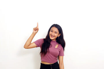 Happy asian girl standing and pointing something at empty space with wow expression.