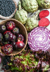 purple and red, violet vegetables on the purple background, top view. purple  artichoke, tomatoes, oniones, blueberries, salad, contain Anthocynins, found in the Okinawan diet, that maintain health