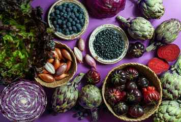 purple and red, violet vegetables on the purple background, top view. purple  artichoke, tomatoes, oniones, blueberries, salad, contain Anthocynins, found in the Okinawan diet, that maintain health