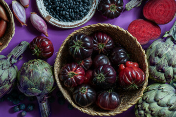 purple and red, violet vegetables on the purple background, top view. purple  artichoke, tomatoes, oniones, blueberries, salad, contain Anthocynins, found in the Okinawan diet, that maintain health