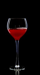 A glass of young wine on a black background.