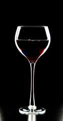 A glass of young wine on a black background.