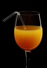Glass of orange juice on a black background.