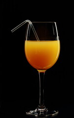 Glass of orange juice on a black background.