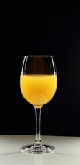 Glass of orange juice on a black background.