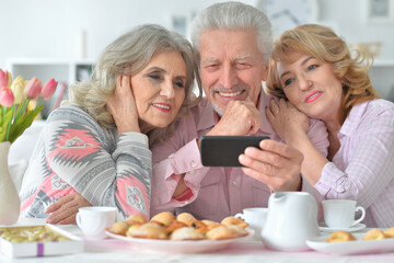 happy senior people with smartphone drinking tea