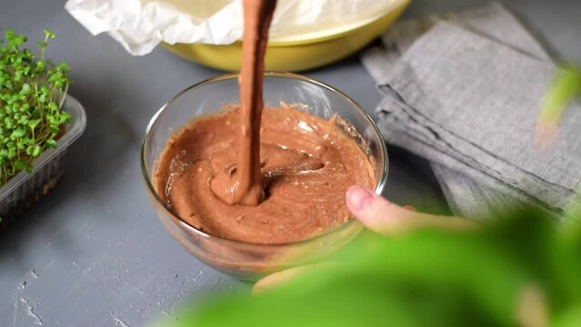 Making liquid chocolate dough for cake, pancakes or pie. Stirring batter with a whisk in the glass bowl. Preparing a dessert