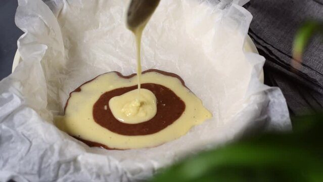 Making marble or zebra cake. Pouring chocolate and white dough step by step into the baking pan to prepare the striped dessert
