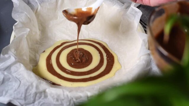 Making marble or zebra cake. Pouring chocolate and white dough step by step into the baking pan to prepare the striped dessert