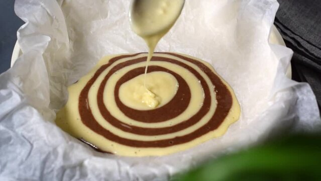Making marble or zebra cake. Pouring chocolate and white dough step by step into the baking pan to prepare the striped dessert