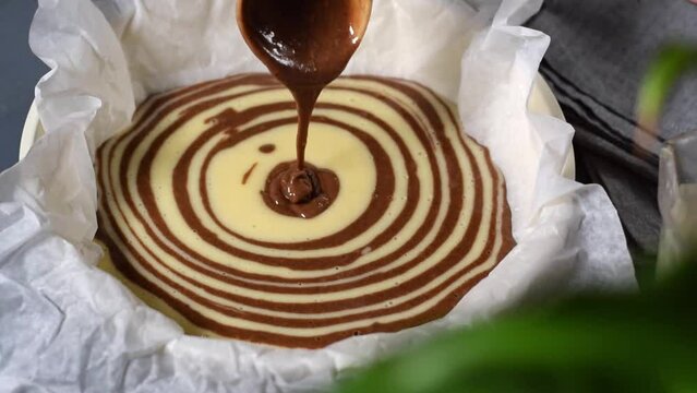 Making marble or zebra cake. Pouring chocolate and white dough step by step into the baking pan to prepare the striped dessert
