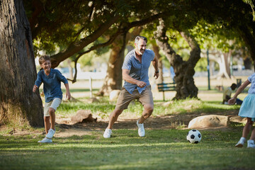 Giving dad a run for his money. Shot of an adorable little boy playing soccer with his father in...