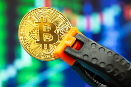 Representative bitcoin coin pinched by pincer in selective focus. Concept of suppressed digital money, bitcoin, decentralized money.