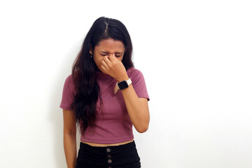Asian young pensive sad girl wearing pink shirt keep eyes closed rub put hand on nose