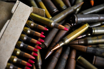 Pile and box of bullets which are new and old on dark background, soft and selective focus.