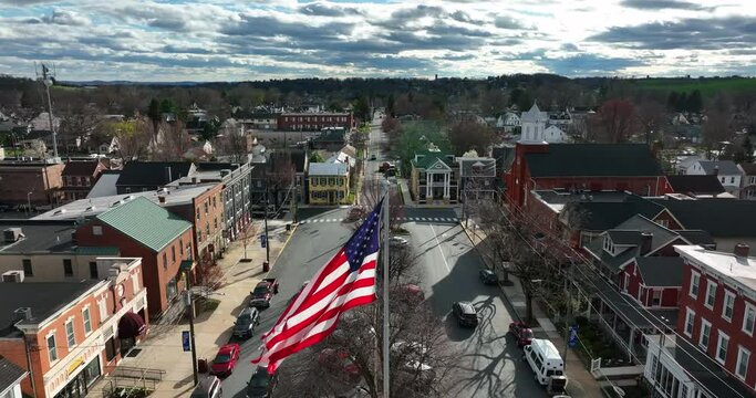 American town on bright sunny day. Bright sunlight transitions to cloudy. Tattered USA and Pennsylvania flag in Manheim Lancaster County.