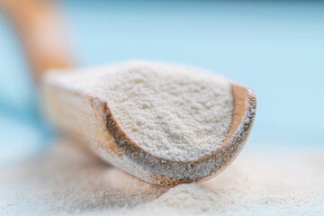 Collagen powder in spoon on wooden blue background close up. Extra protein intake. Natural beauty and health supplement