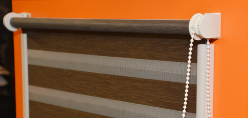 A close-up of a striped roller blind for a window, roller zebra blind, shutter installed on a...