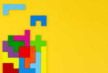 Fototapeta premium Different colorful shapes wooden puzzle blocks on yellow background. Geometric shapes in different colors, top view, copy space