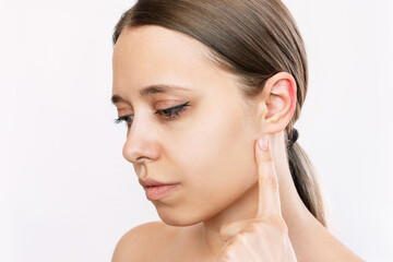 Portait of a young caucasian woman pointing at her ear with her finger isolated on a white...