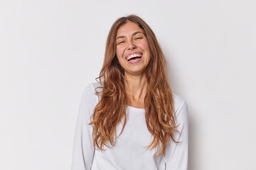 Positive human emotions concept. Long haired young European woman with piercing smiles toothily dressed in casual jumper isolated over white background. Cheerful female model poses in studio