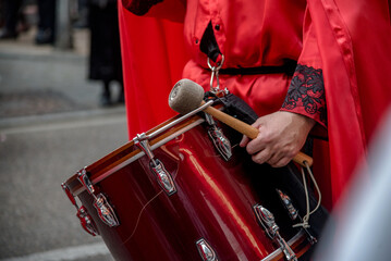 Miembro de la banda de música de la cofradía de La Preciosísima Sangre de Valladolid, España, tocando el tambor durante una procesión de Semana Santa.  - obrazy, fototapety, plakaty