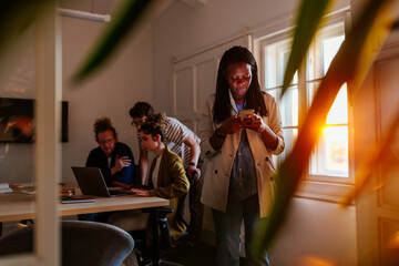 Afro businesswoman typing on a cellphone indoors