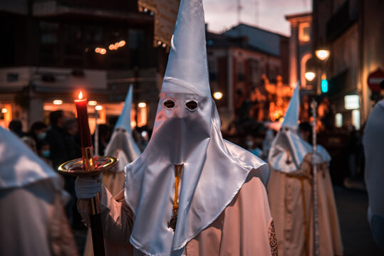 Cofrade ataviado con la indumentaria de la cofrad&iacute;a de 'La Sagrada Cena', h&aacute;bito beige y capirote blanco, mirando a c&aacute;mara durante una procesi&oacute;n de la Semana Santa de Valladolid.