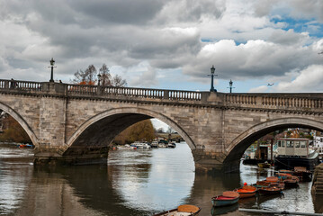 Fototapeta na wymiar Old ancient traditional English stone bridge over calm countryside river