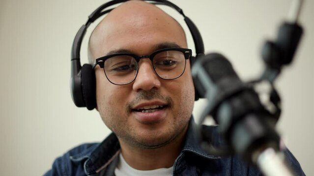 Content creator man host streaming his a podcast on laptop with headphones and microphone interview cheering guest conversation at home broadcast studio. Blogger motivation recording voice over radio