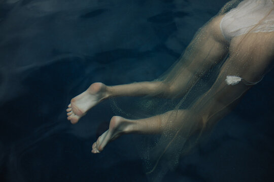 Legs and butt floating underwater wearing sparkly dress