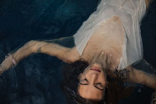 Meditating young woman floating in ocean water with arms outstretched