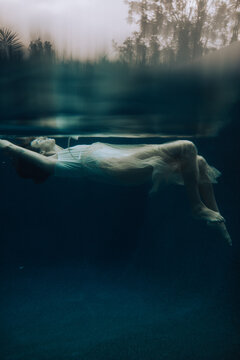 Sensual woman floating underwater facing the sun
