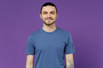 Obraz premium Young smiling attractive cheerful happy fun cool man 20s wearing blue t-shirt with blank print design look camera isolated on plain purple color background studio portrait. People lifestyle concept