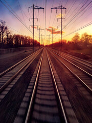 Traveling on railroad train tracks into setting sunlight on the distant horizon