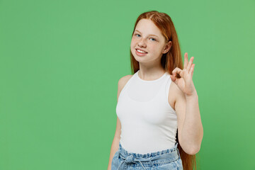 Little redhead kid satisfied happy smiling girl 12-13 years old wearing white tank shirt showing...