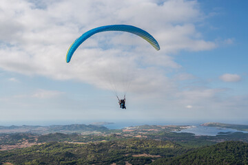 First flight with a tandem paragliding instructor. Photo taken from the El Toro lookout point, municipality of Es Mercadal, Menorca, Spain - Powered by Adobe