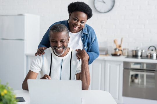 happy african american man and woman looking at laptop.