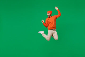 Full size young exultant happy overjoyed excited fun cool man 20s in orange sweatshirt hat jump...
