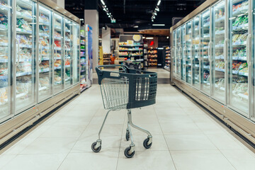 Supermarket aisle with empty black shopping cart © bernardbodo