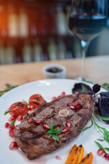 grilled ribeye beef steak with spice or herb on white plate on restaurant table