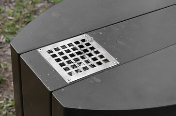 On the square in the park, these metal trash cans have an ashtray for smokers
