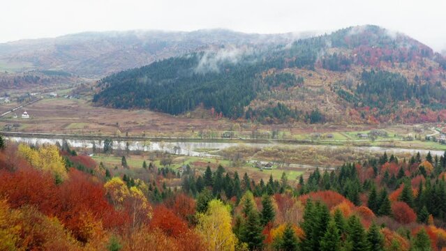 Aerial Drone View of vivid autumn natural landscape. Mountains, colorful trees in forest, fiver and haze above it