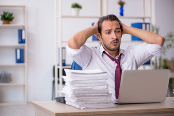 Fototapeta premium Young male employee and too much work in the office