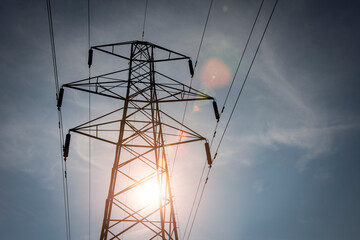 Electricity pylon and power cables with sun flare.