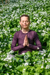 Naklejka na ściany i meble Yoga Meditation Outdoors in Lotus Position in a field of flowering wild garlic